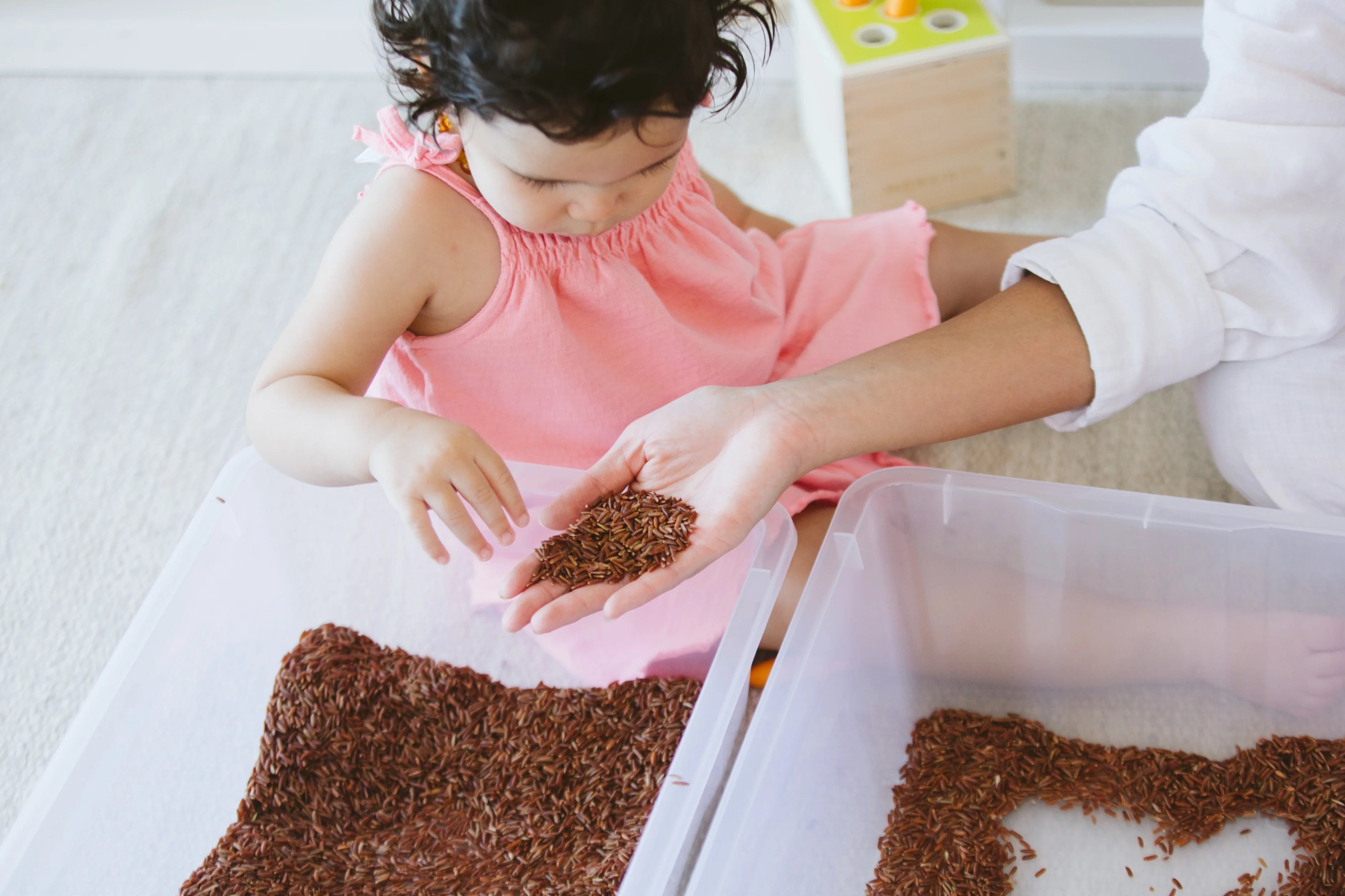 Toddler engaged in messy play with sensory bin, illustrating the importance of sensory play for development