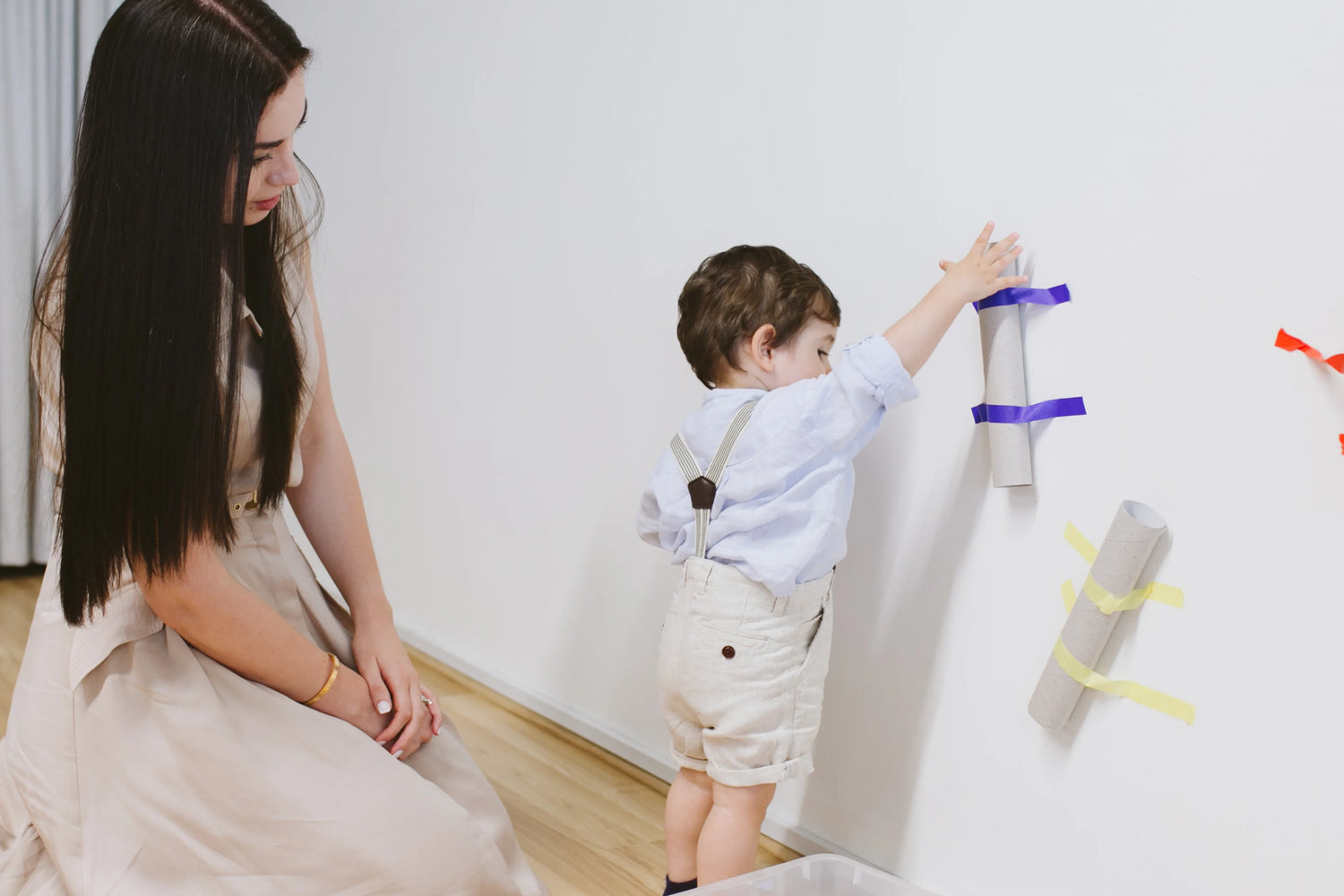 Mom helping toddler throw a toy into a box, demonstrating a fun activity to teach basic concepts of gravity