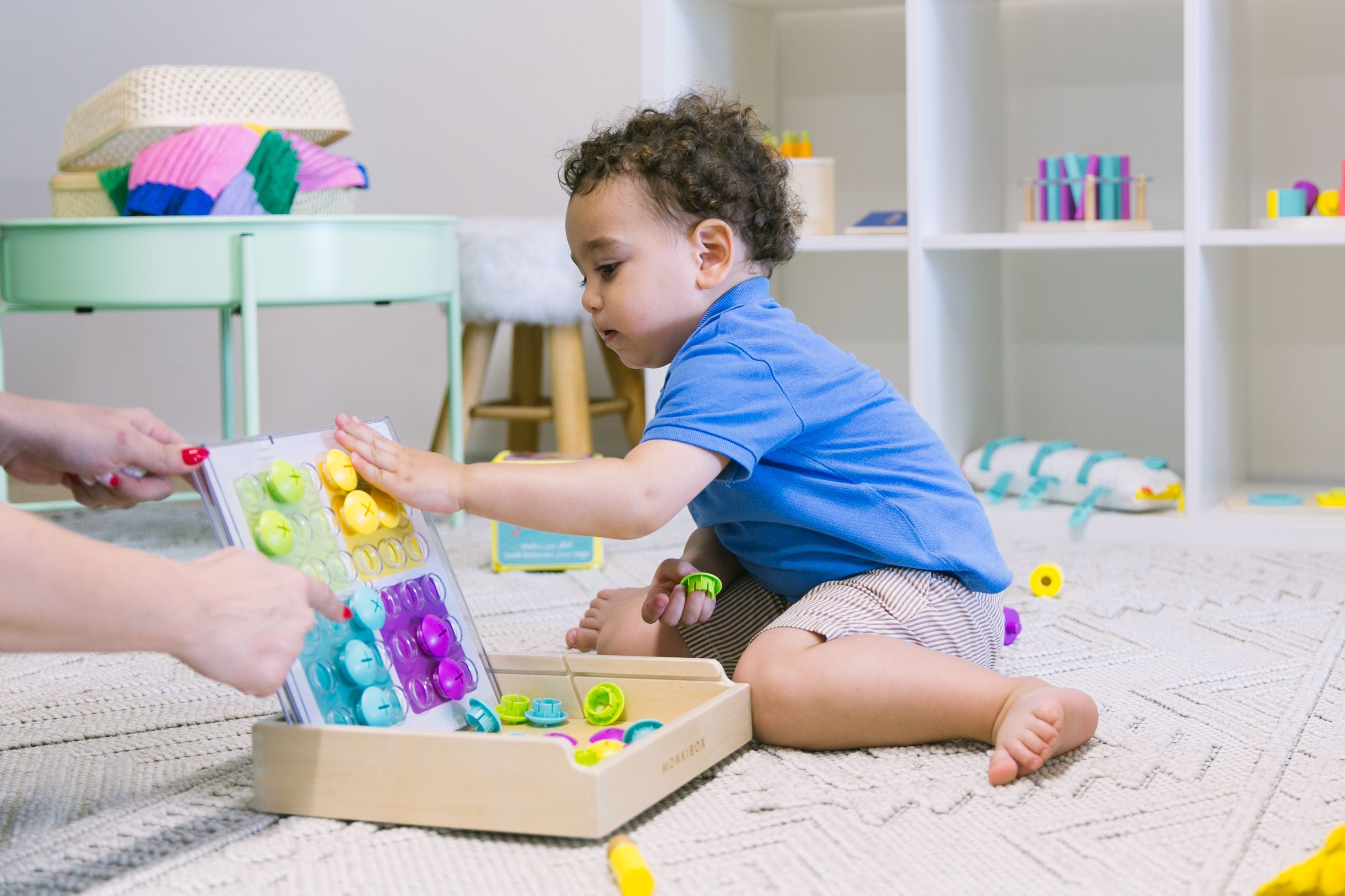 Toddler engaging with a sorting toy featuring colorful buttons, practicing pattern recognition and sorting skills—activities that help introduce math concepts through play.