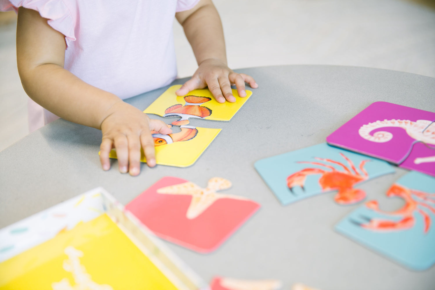 Toddler's hand bringing together a two piece puzzle 