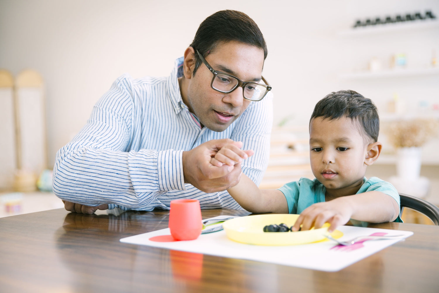 father guiding toddler through mealtime and navigating toddler's behavior with food